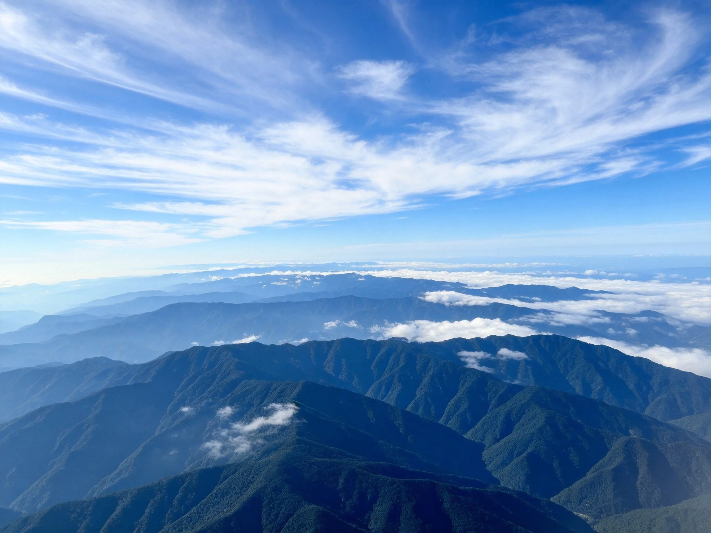 Vibrant blue sky over layered green mountain ranges