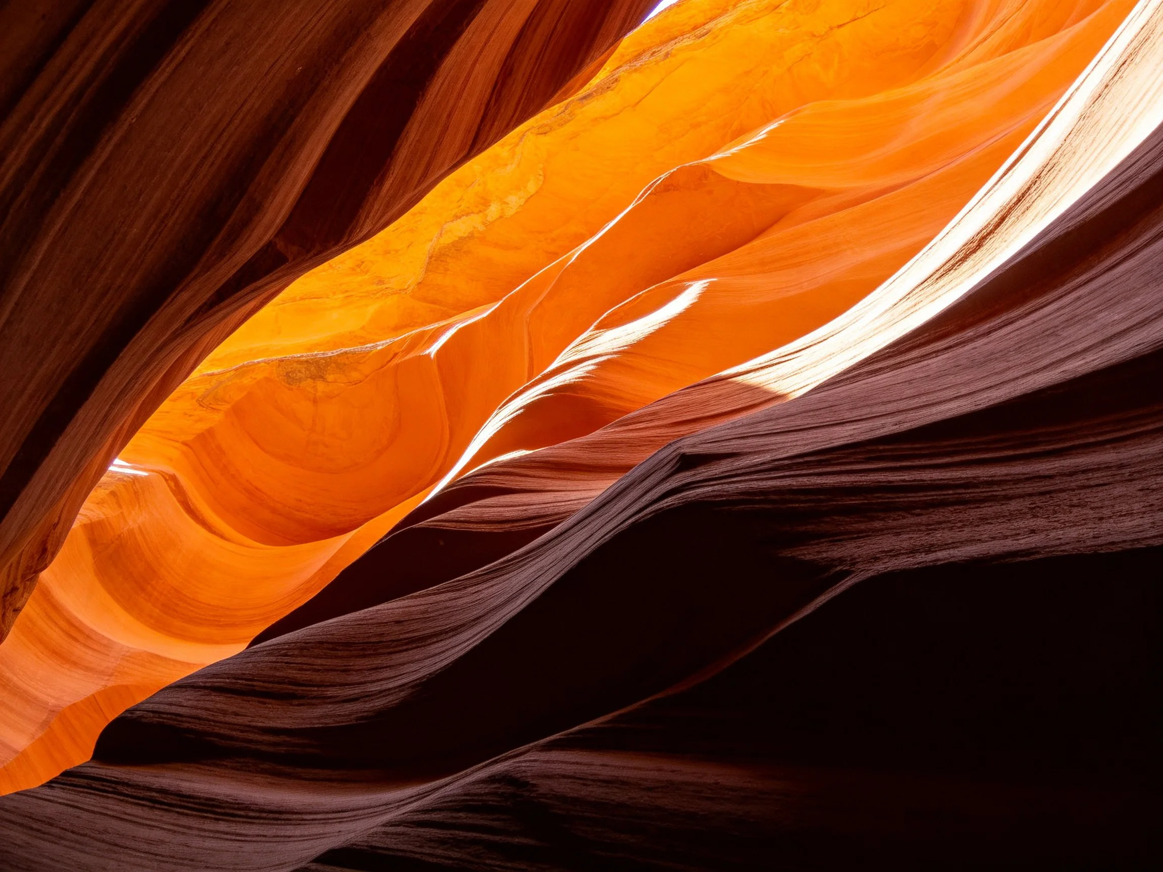 Vibrant orange and dark brown slot canyon formations with dramatic lighting