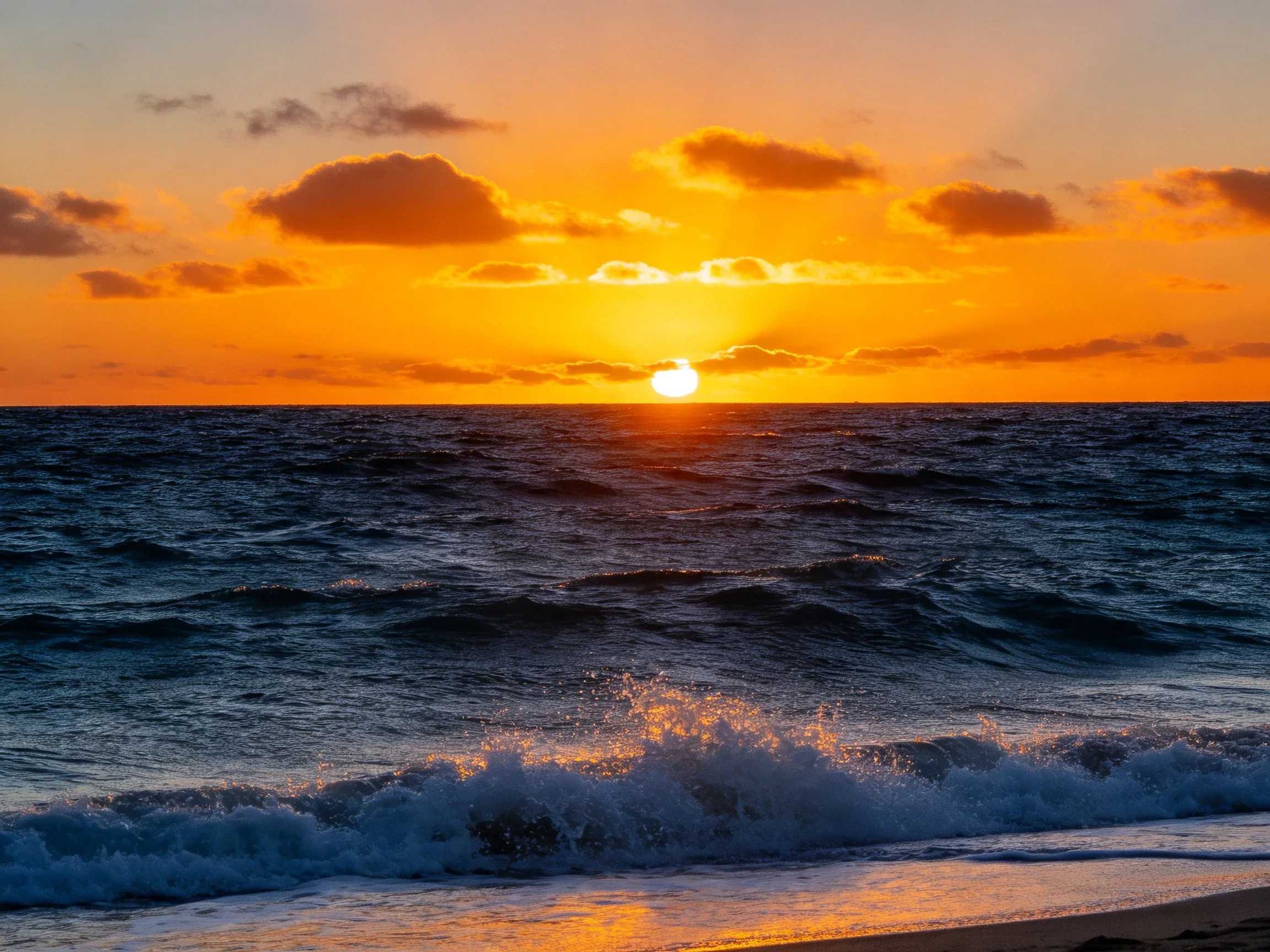 Vibrant orange sunset over dark blue ocean waves