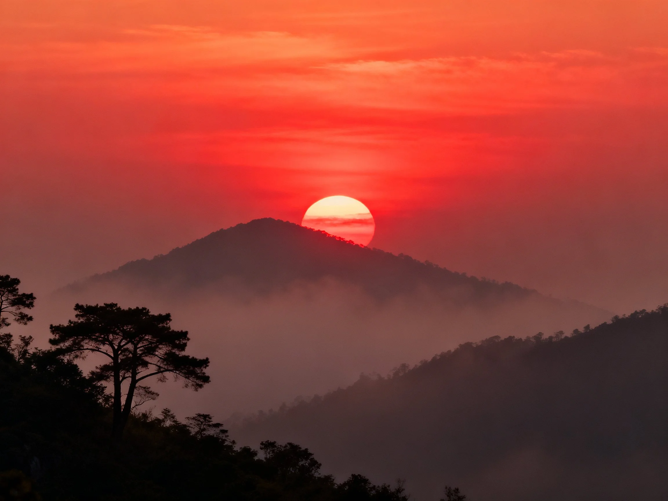 Vibrant red sunset over misty mountain ridges
