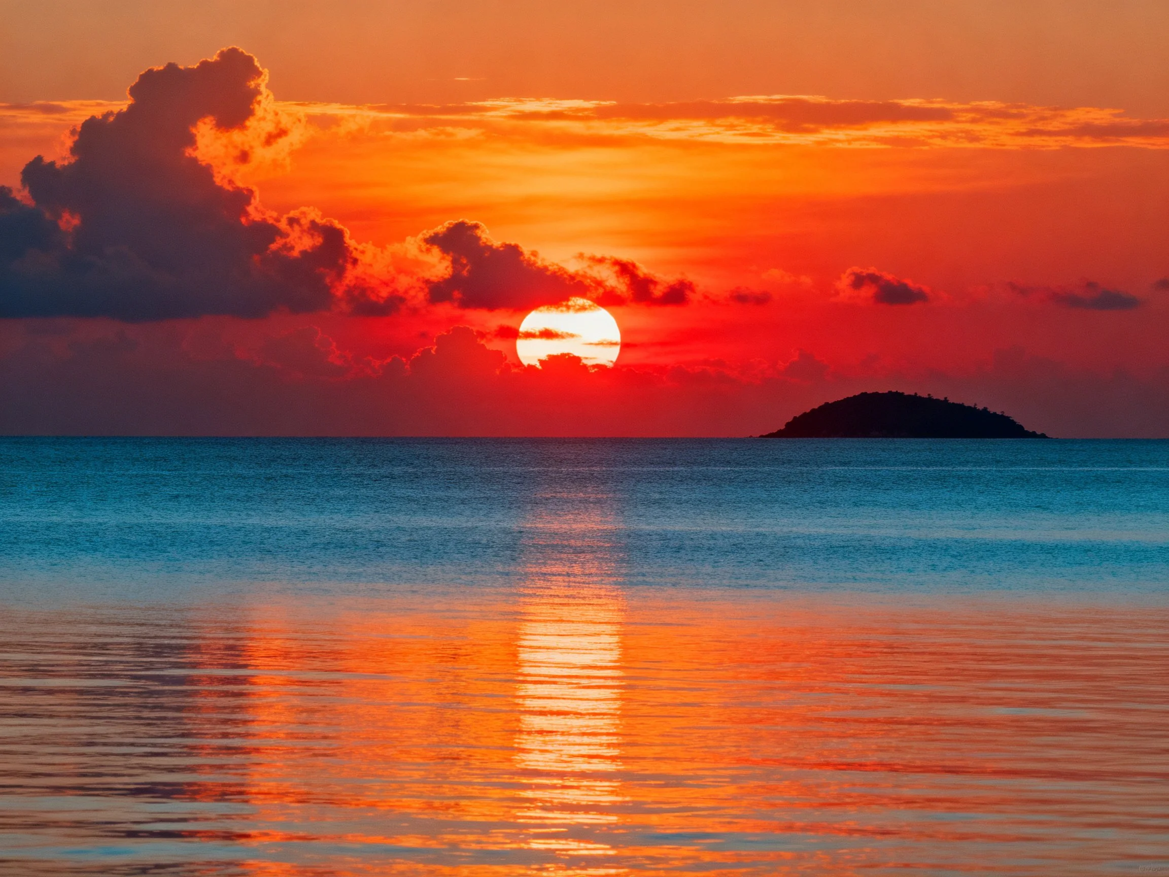 Vibrant sunset hues reflect on calm ocean waters near small island