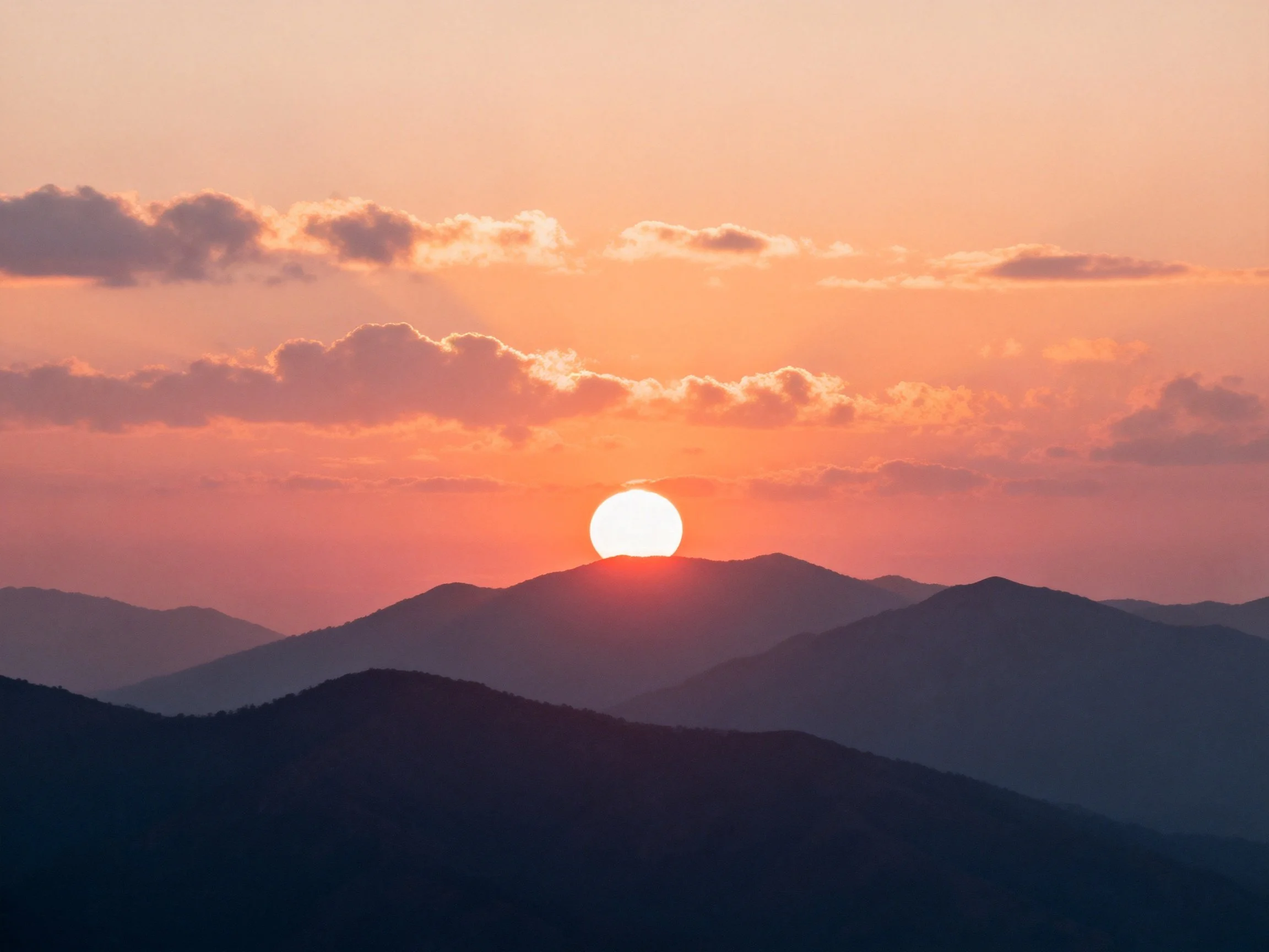 Vibrant sunset over layered mountain silhouettes