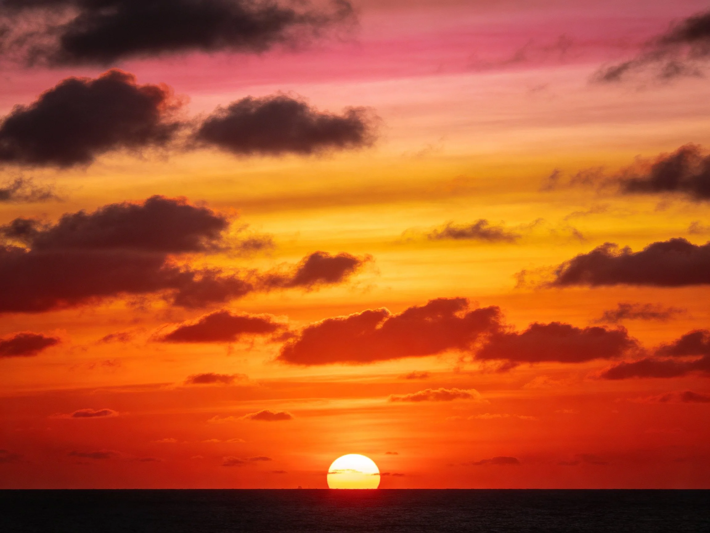 Vibrant sunset over ocean with multicolored sky and dark clouds