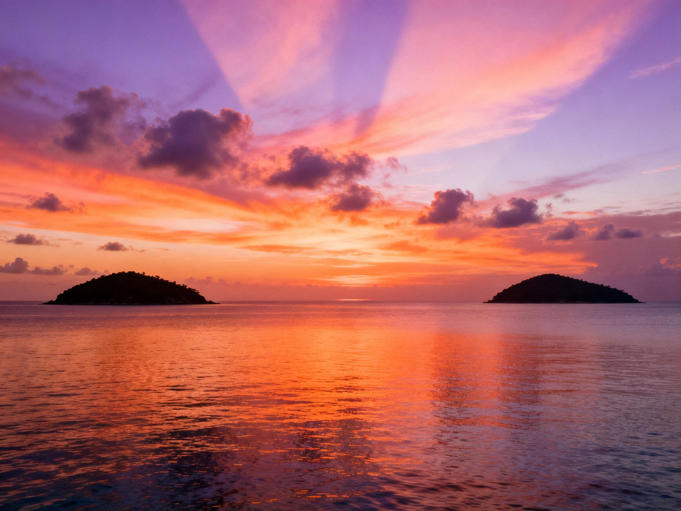 Vibrant sunset sky over calm sea with two islands