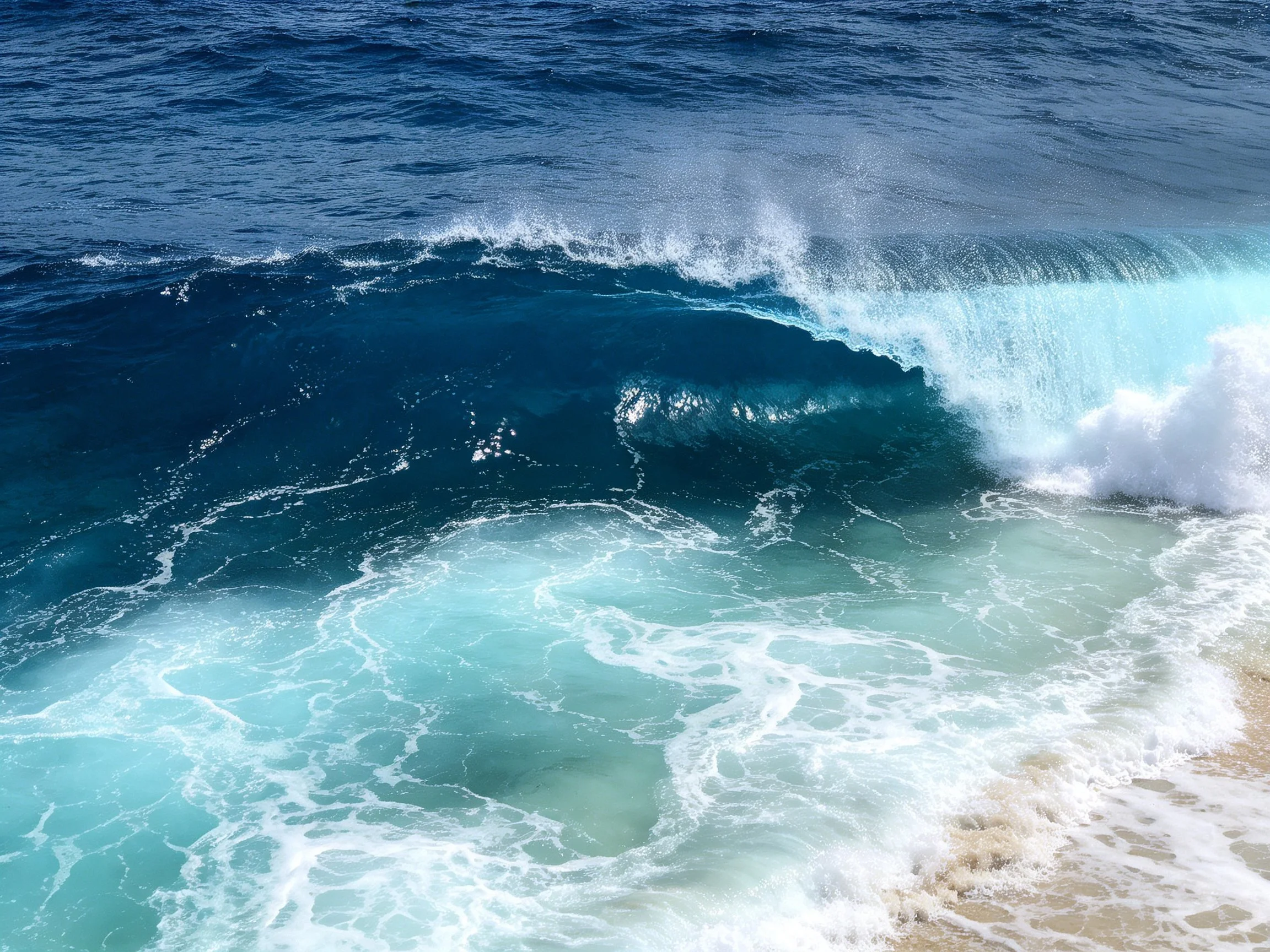 Vibrant turquoise and deep blue ocean waves break near shoreline