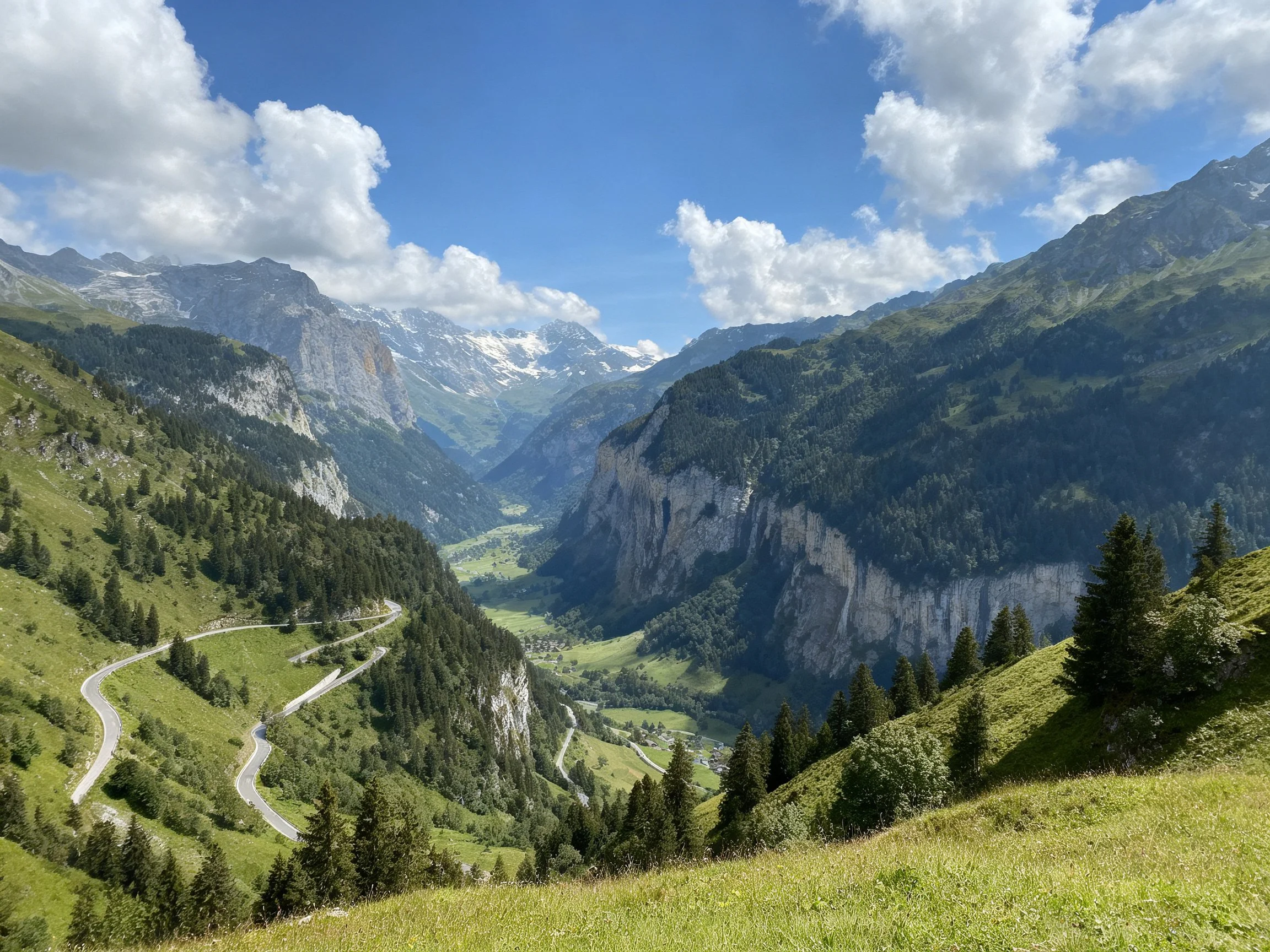 Winding Road Through Mountain Valley with Lush Greenery and Cliffs