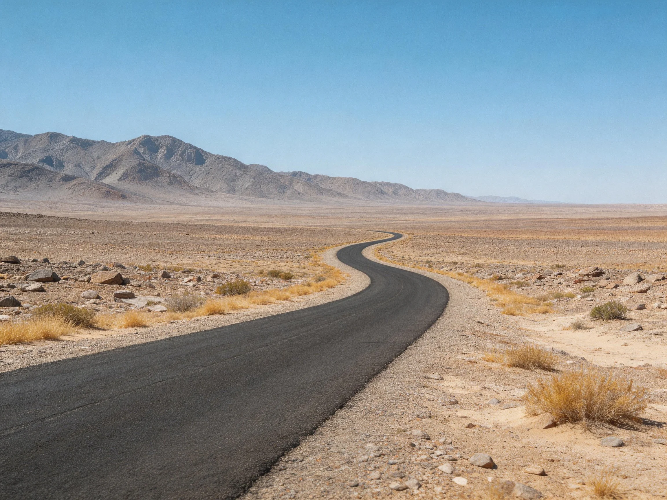 Winding asphalt road through ar arid desert toward distant mountains