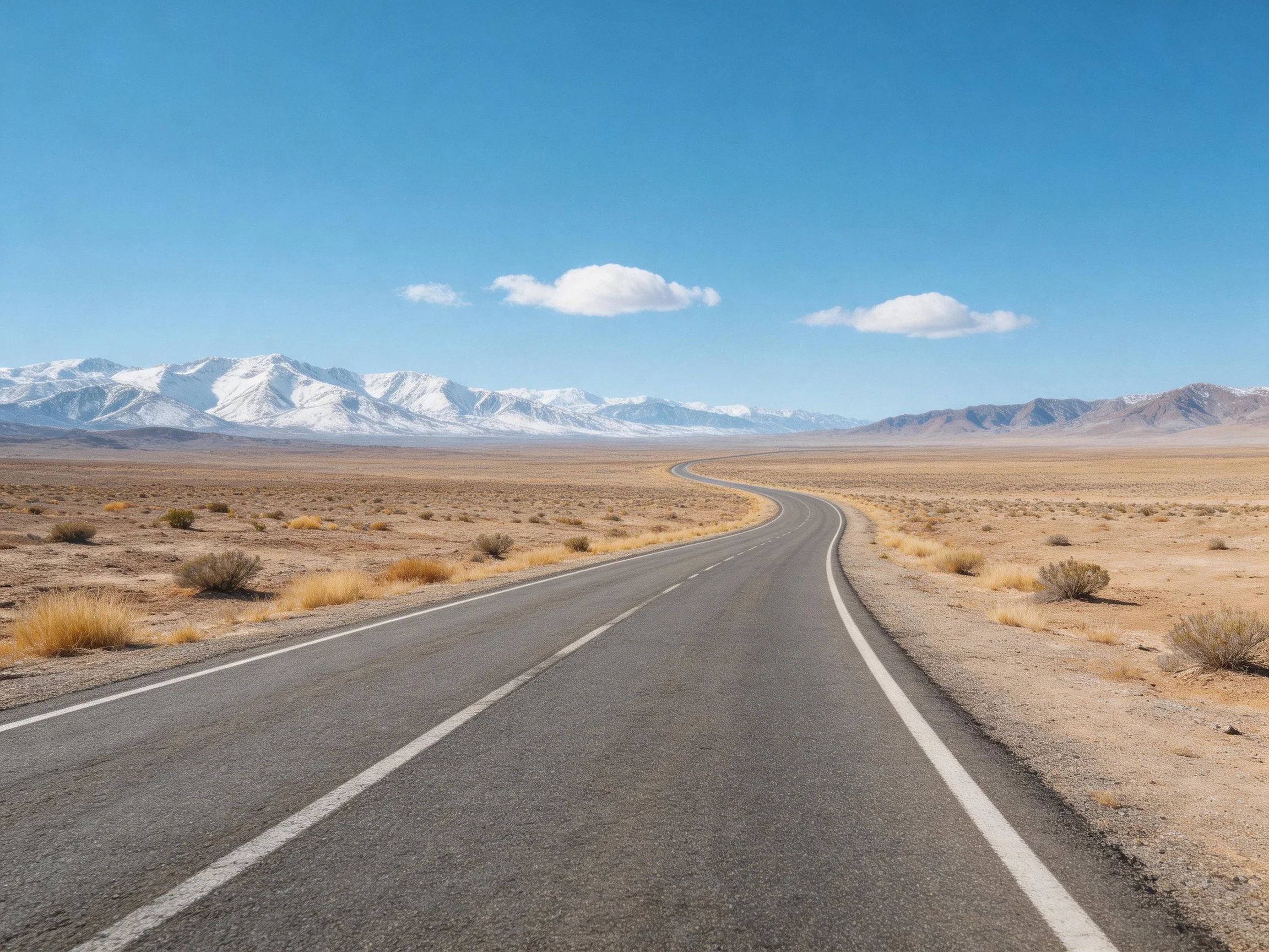 Winding asphalt road through dry plains near snow - covered peaks