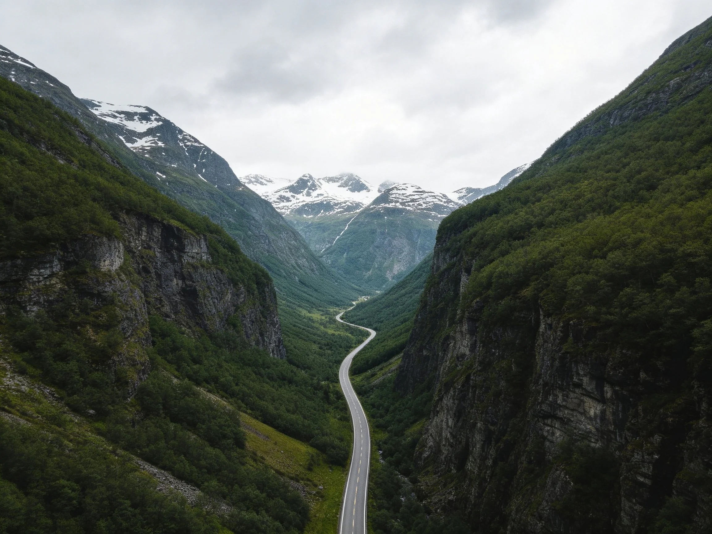 Winding road through lush green valleys toward snow-capped mountains