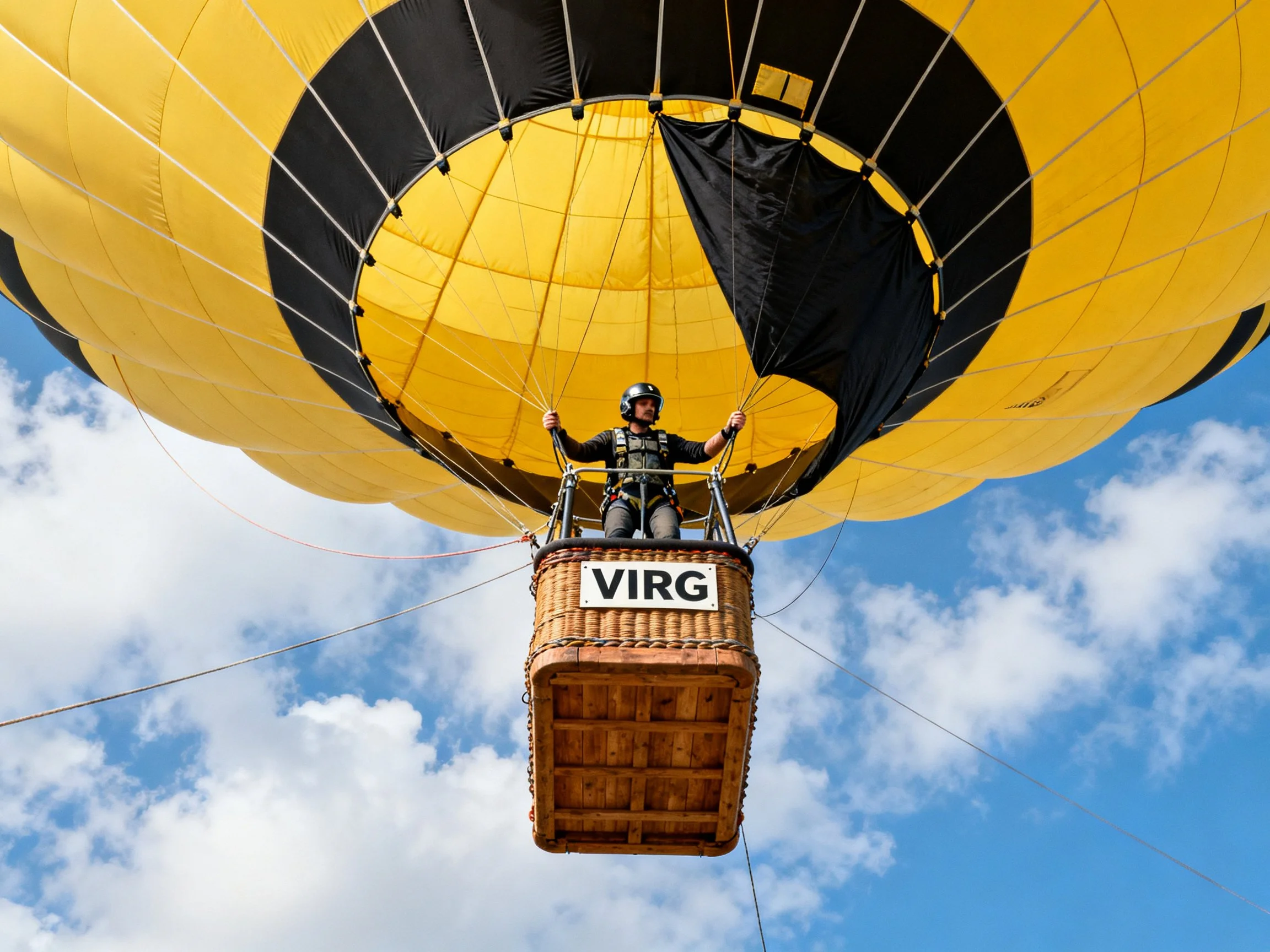 Yellow and black hot air balloon with pilot in wicker basket